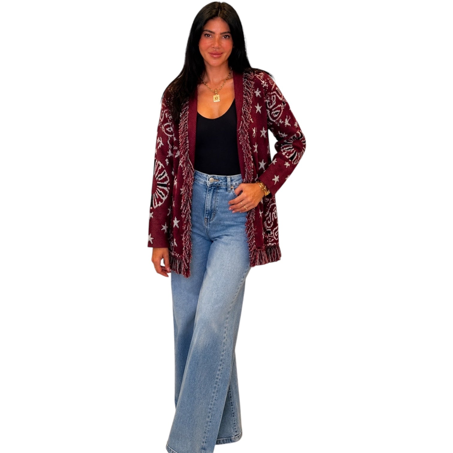 A woman modeling a long-sleeve open-front cardigan with a burgundy and white paisley pattern, worn over a black tank top and light-wash blue jeans, against a plain white background.