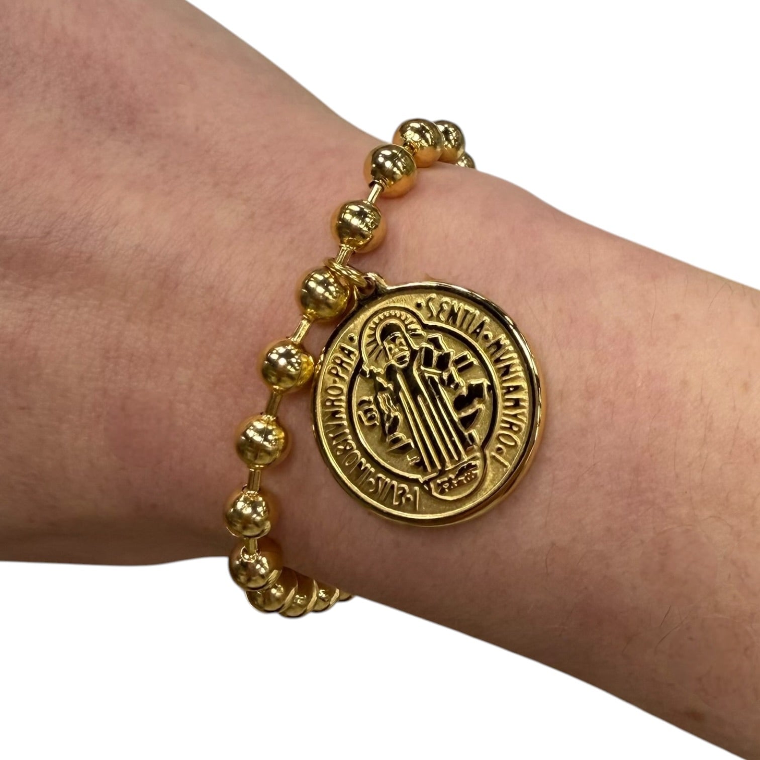 Gold bracelet with a medallion on a wrist against a white background
