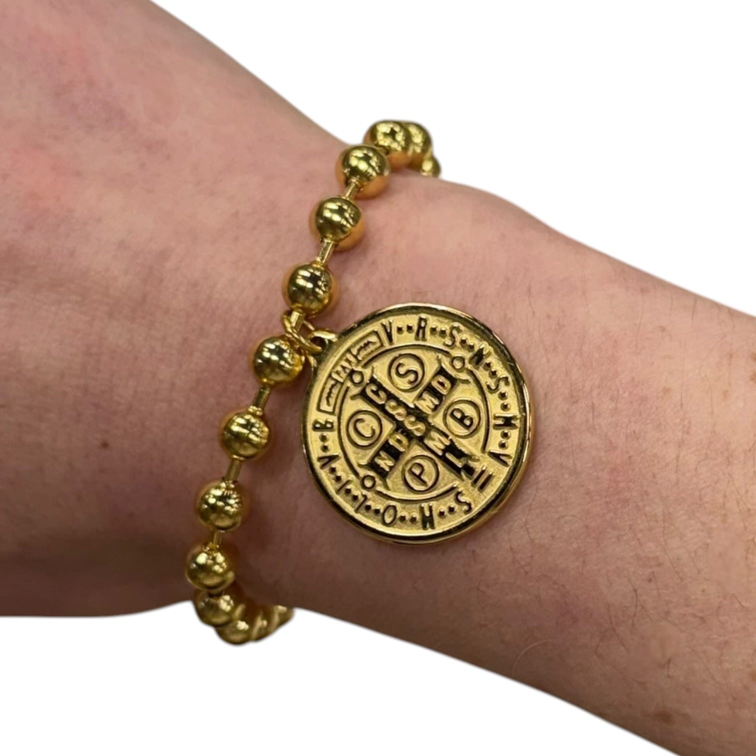 Gold bracelet with a circular emblem on a wrist against a white background