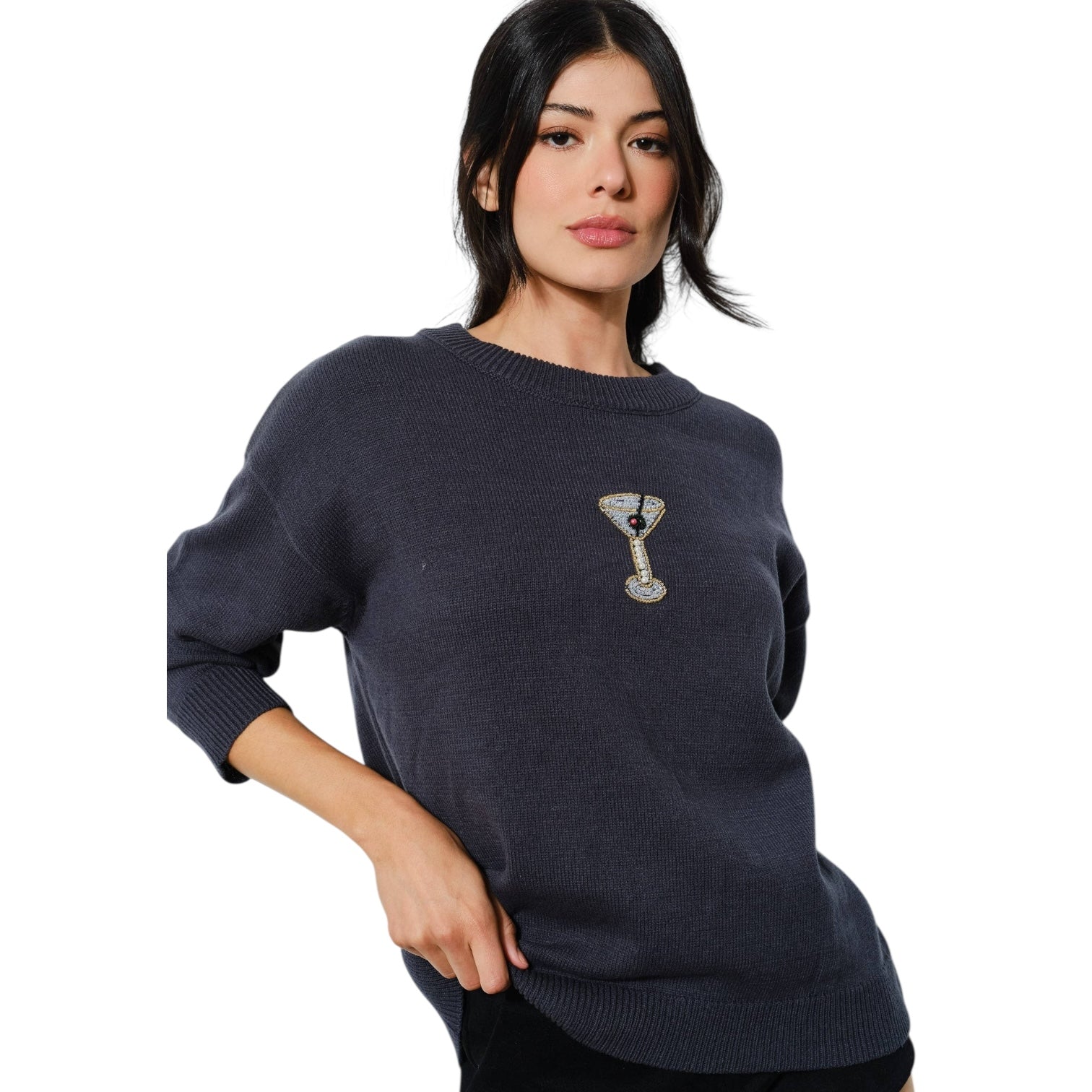 Woman wearing a navy blue sweater with a beaded martini on a white background