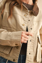 Close-up of a person wearing a beige jacket with buttons.
