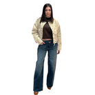 Woman wearing a beige jacket and blue jeans on a white background