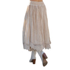 Beige lace skirt worn with white pants and brown shoes on a white background