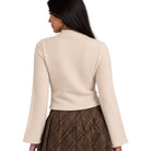 A woman shown from the back wearing a light beige knit mock-neck sweater and a brown plaid skirt, against a plain white background.