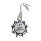 A decorative ornament featuring a circular white center with the text 'WORLD'S BEST GRANDMA' and a silver filigree border, hanging from a sheer silver ribbon on a white background.