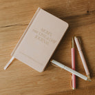 Journal titled 'Mom's One Line a Day Journal' with two pens on a wooden surface