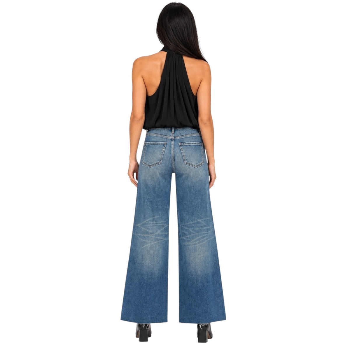 A woman shown from the back wearing a black halter top and wide-leg blue denim jeans with faded whiskering on the upper thighs, set against a plain white background.