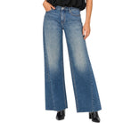 A woman modeling a black sleeveless halter top and wide-leg blue jeans against a plain white background.