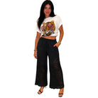 Woman wearing a white t-shirt with a graphic design and black lace pants on a white background