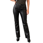 Black faux leather straight-leg pants worn by a model, paired with a leopard-print top and black pointed-toe boots, shown against a plain white background.