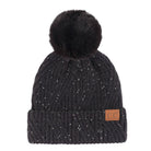 A black ribbed knit beanie hat with a fluffy black faux fur pom-pom on top, decorated with tiny silver glitter specks, featuring a small brown leather patch with 'CC' on the folded cuff.