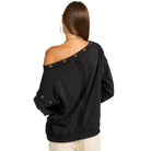 Black off-shoulder top with button details on a white background
