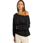 Woman wearing a black off-shoulder top with button details on a white background