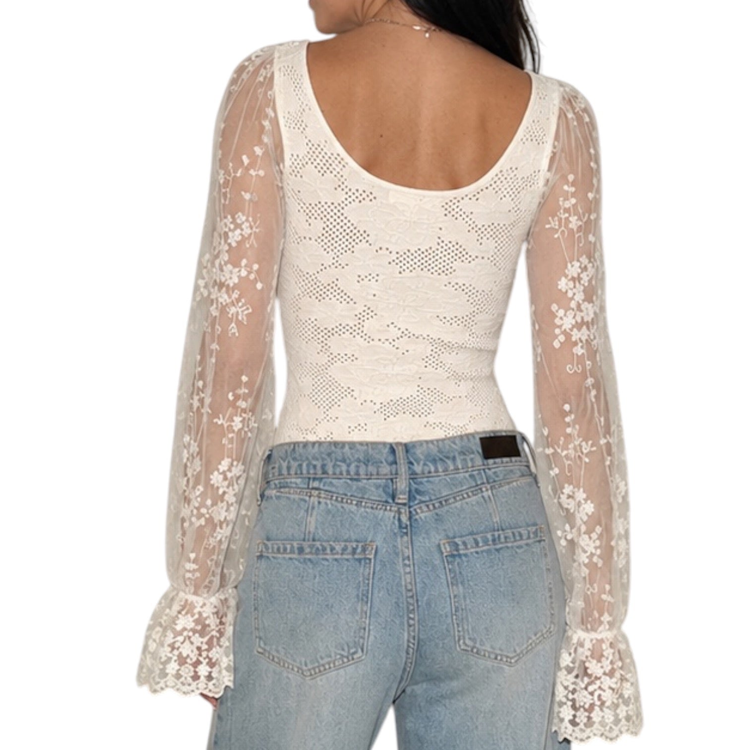 A woman shown from the back wearing a cream lace long-sleeve scoop-neck top with sheer floral lace sleeves and light-wash blue jeans against a plain white background.