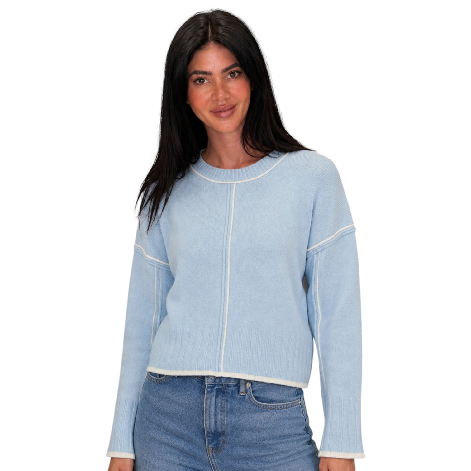 A woman modeling a light blue cropped knit sweater with contrasting white stitching details, paired with blue jeans, against a plain white background.