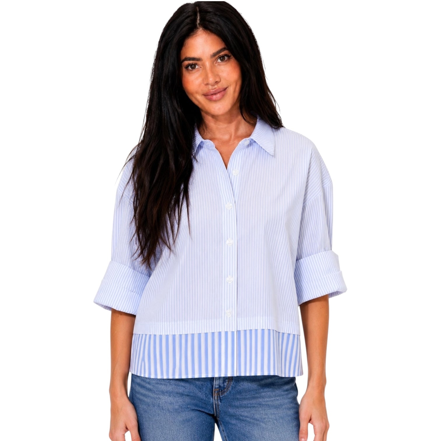 A woman modeling a light blue and white vertically striped button-down shirt with rolled-up sleeves and a matching striped hem detail, paired with blue jeans against a plain white background.