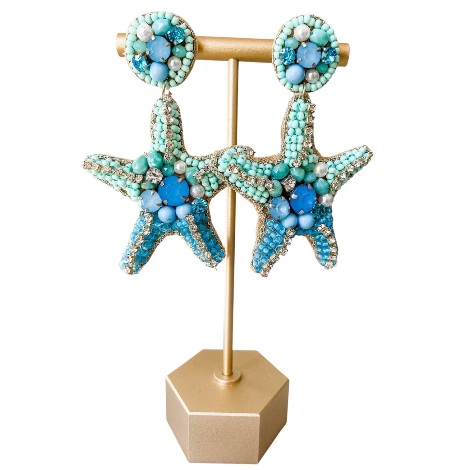 Starfish-shaped earrings with turquoise and blue beads on a gold stand against a white background
