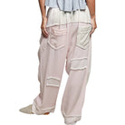 Light pink patchwork pants with decorative stitching on a white background