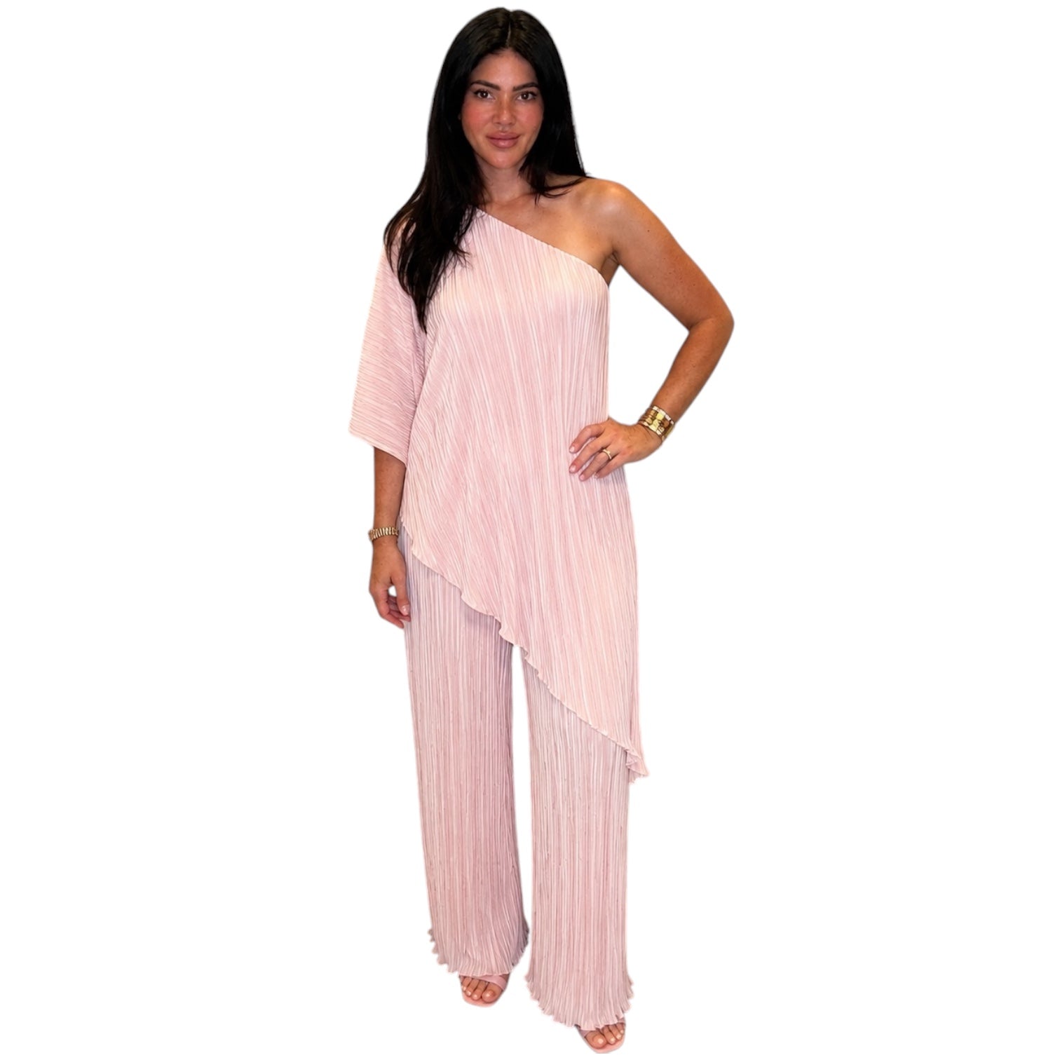 Woman wearing a light pink one-shoulder top and wide-leg pants on a white background