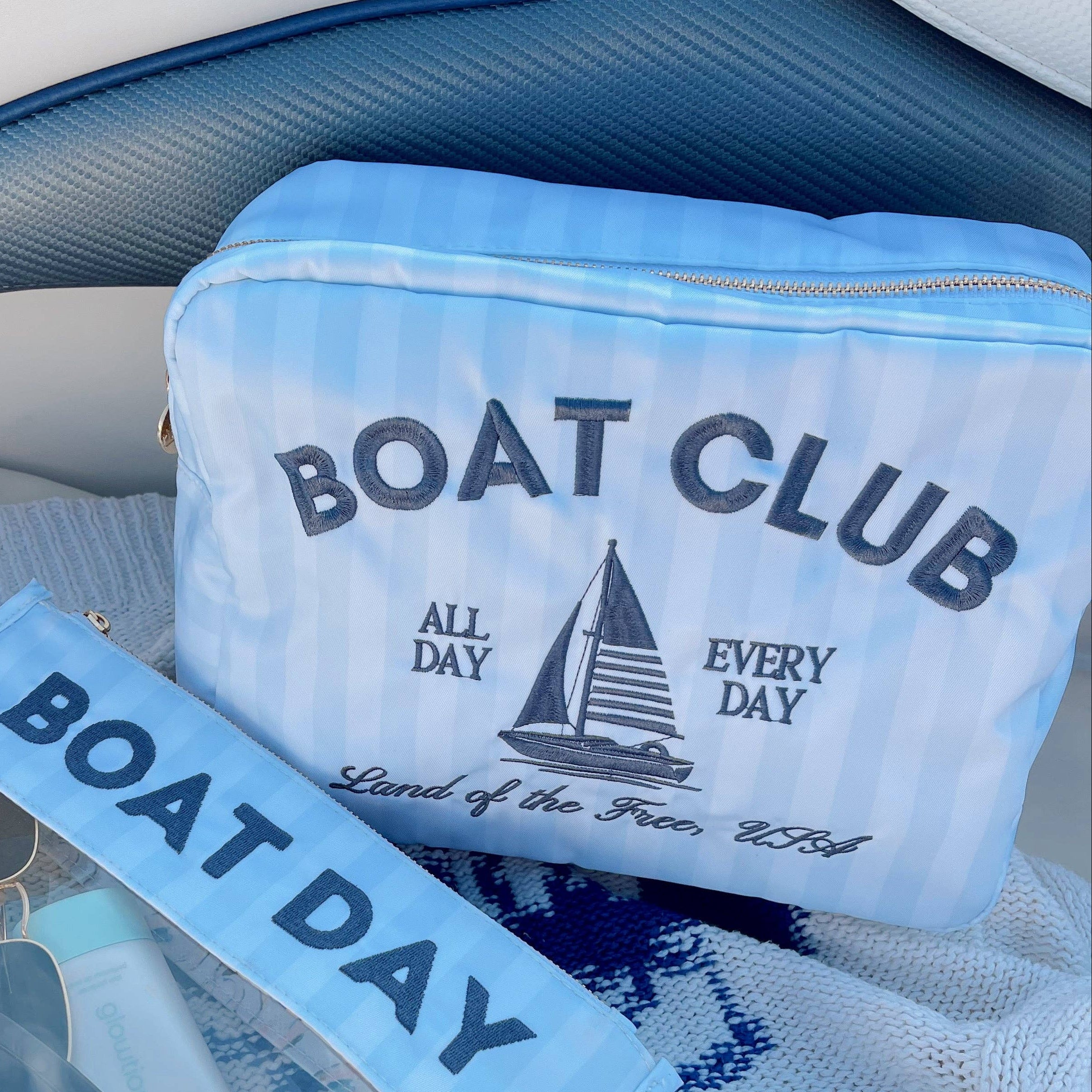 Two blue pouches with 'Boat Club' and 'Boat Day' text on a white surface.