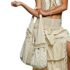Person wearing a beige crochet outfit with a matching bag on a white background
