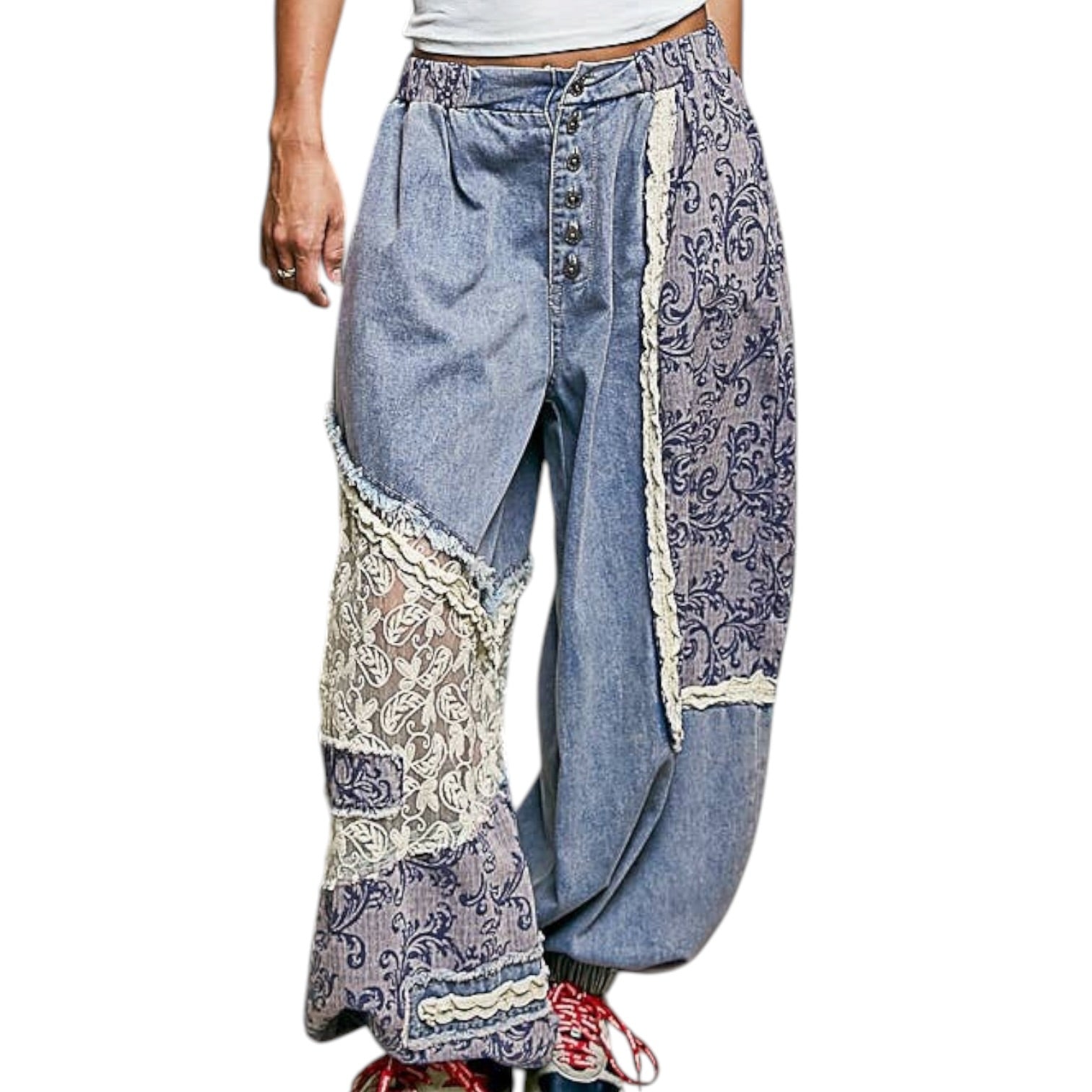 Denim pants with lace and paisley patterned patches on a white background