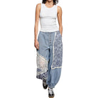 Woman wearing a white sleeveless top and blue patterned pants on a white background