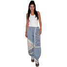 Woman wearing a white tank top and blue floral-patterned pants on a white background