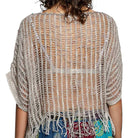 Back view of a person wearing a beige crochet shrug with tassels on a white background
