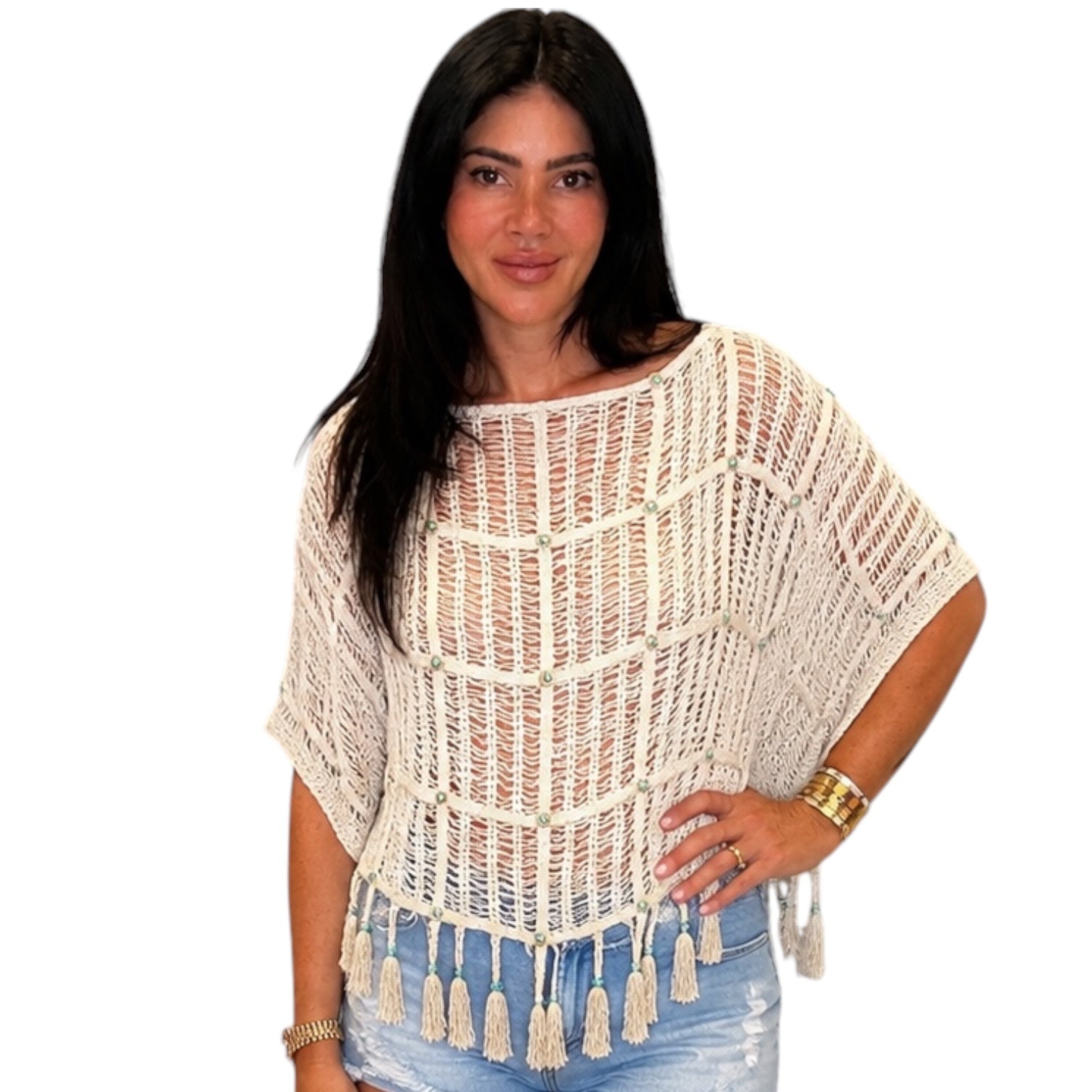 Woman wearing a beige crochet top with tassels on a white background
