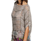 Woman wearing a textured, patterned poncho on a white background