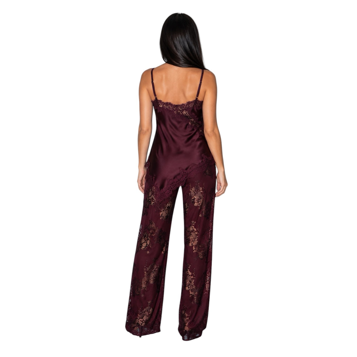 A woman viewed from the back wearing a burgundy satin jumpsuit with floral lace detailing on the bodice and wide legs, set against a plain white background.