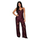 A woman modeling a two-piece satin pajama set in deep burgundy with gold floral lace patterns and ruffle trim, set against a plain white background.