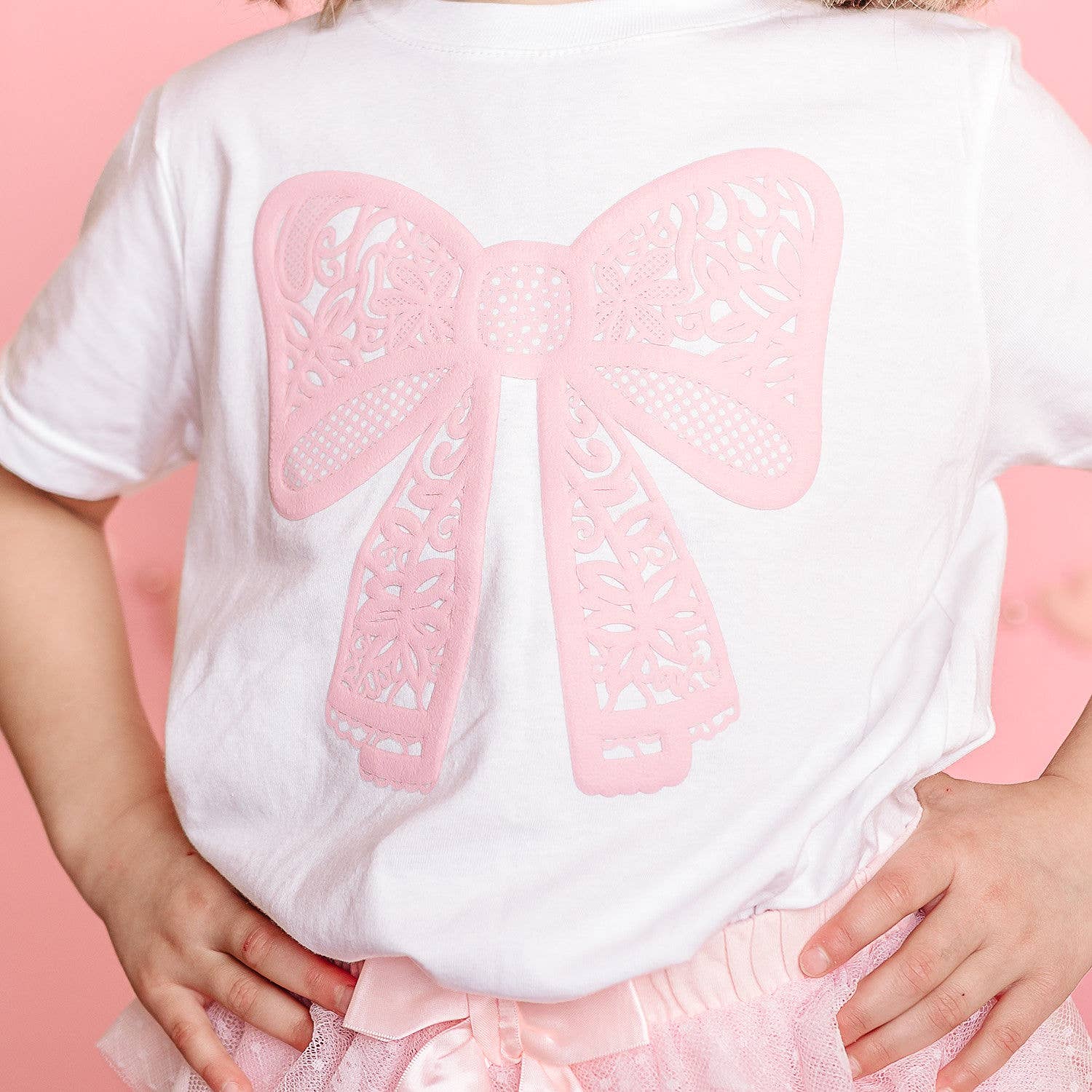 White shirt with pink bow design on a pink background