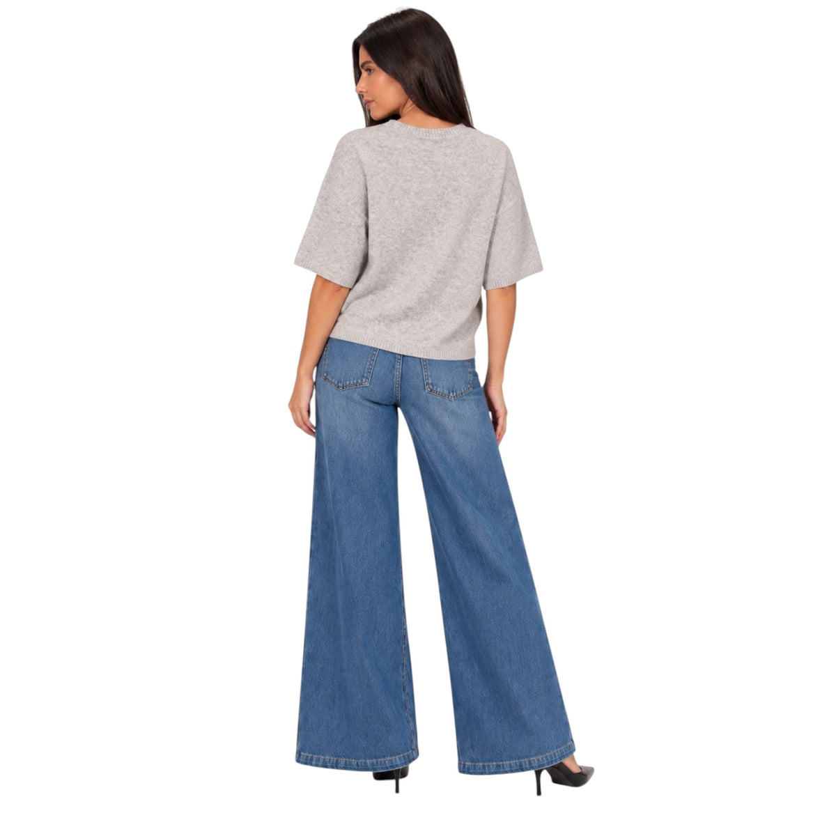 A woman shown from the back wearing a light gray short-sleeve top and wide-leg blue jeans, standing against a plain white background.