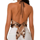 Woman wearing a halter top with geometric pattern and white pants on a white background