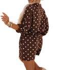 Woman in a polka dot dress and hat standing on a street.