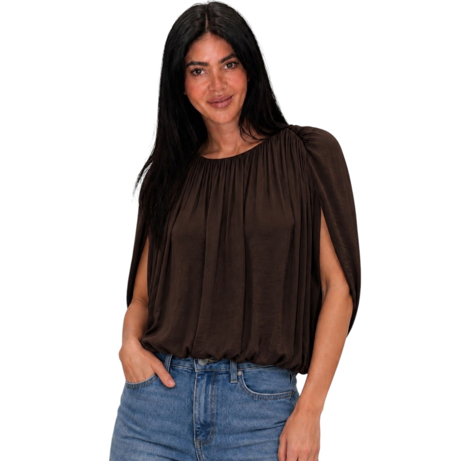 A woman modeling a dark brown pleated top with draped cap sleeves, paired with blue jeans, against a plain white background.