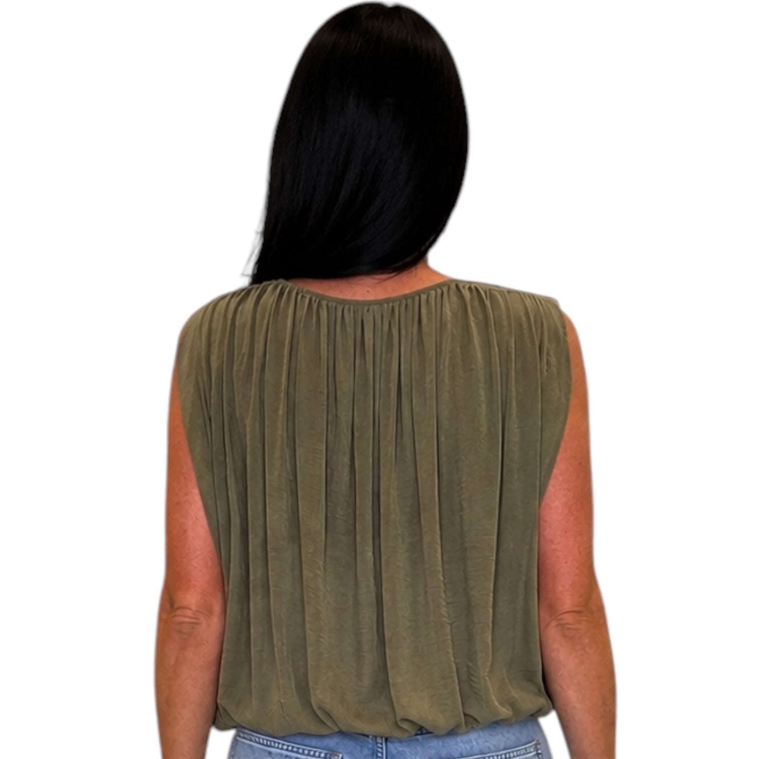 A woman viewed from the back wearing a sleeveless olive green top with a gathered, pleated back design and light blue jeans, set against a plain white background.