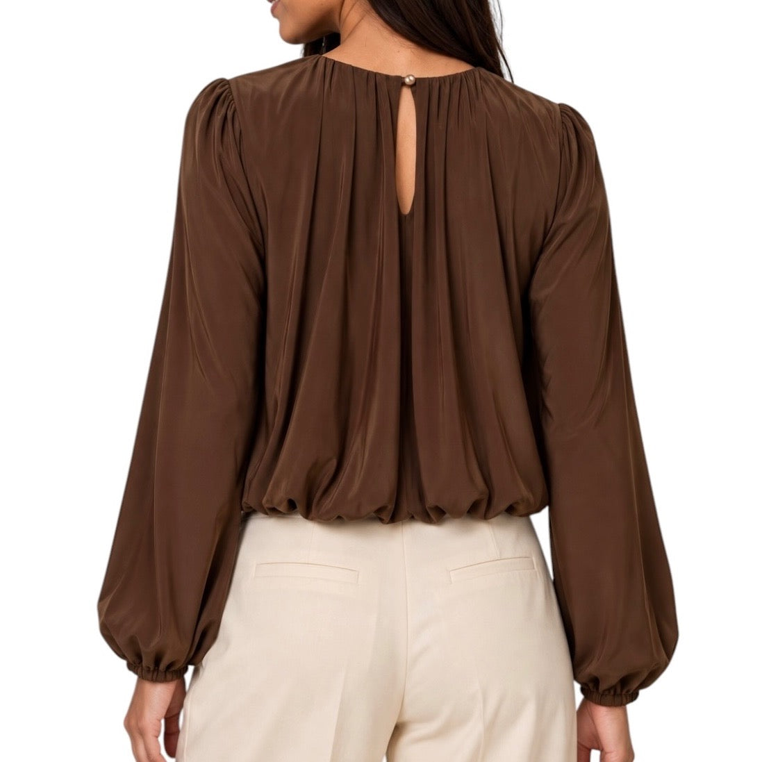 A woman shown from the back wearing a brown long-sleeve blouse with a keyhole back cutout and cream-colored pants, set against a plain white background.