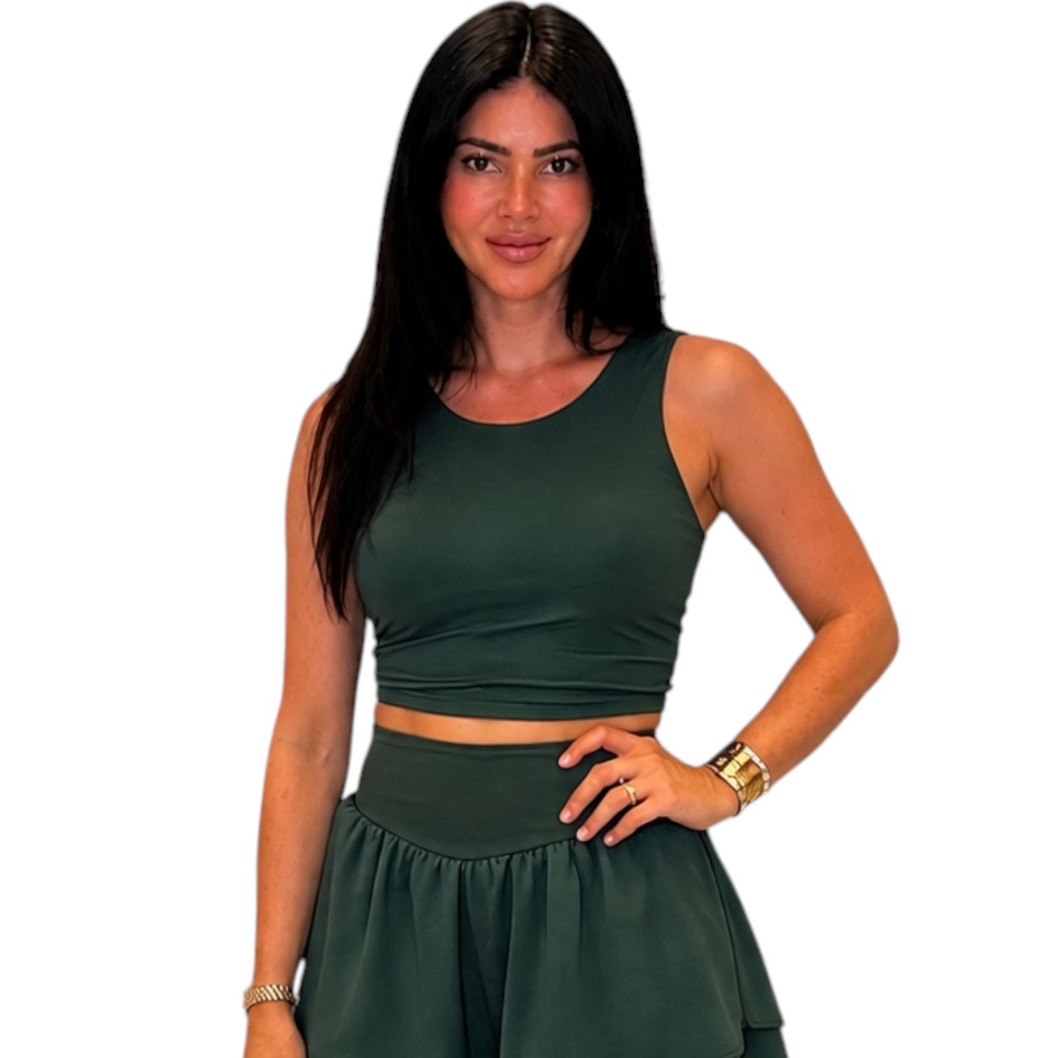 A woman modeling a dark green two-piece set consisting of a sleeveless crop top and a matching high-waisted flared skirt, set against a plain white background.