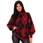 A woman wearing a red and black argyle knit turtleneck sweater with white dotted accent lines, paired with black leather pants, against a plain white background.