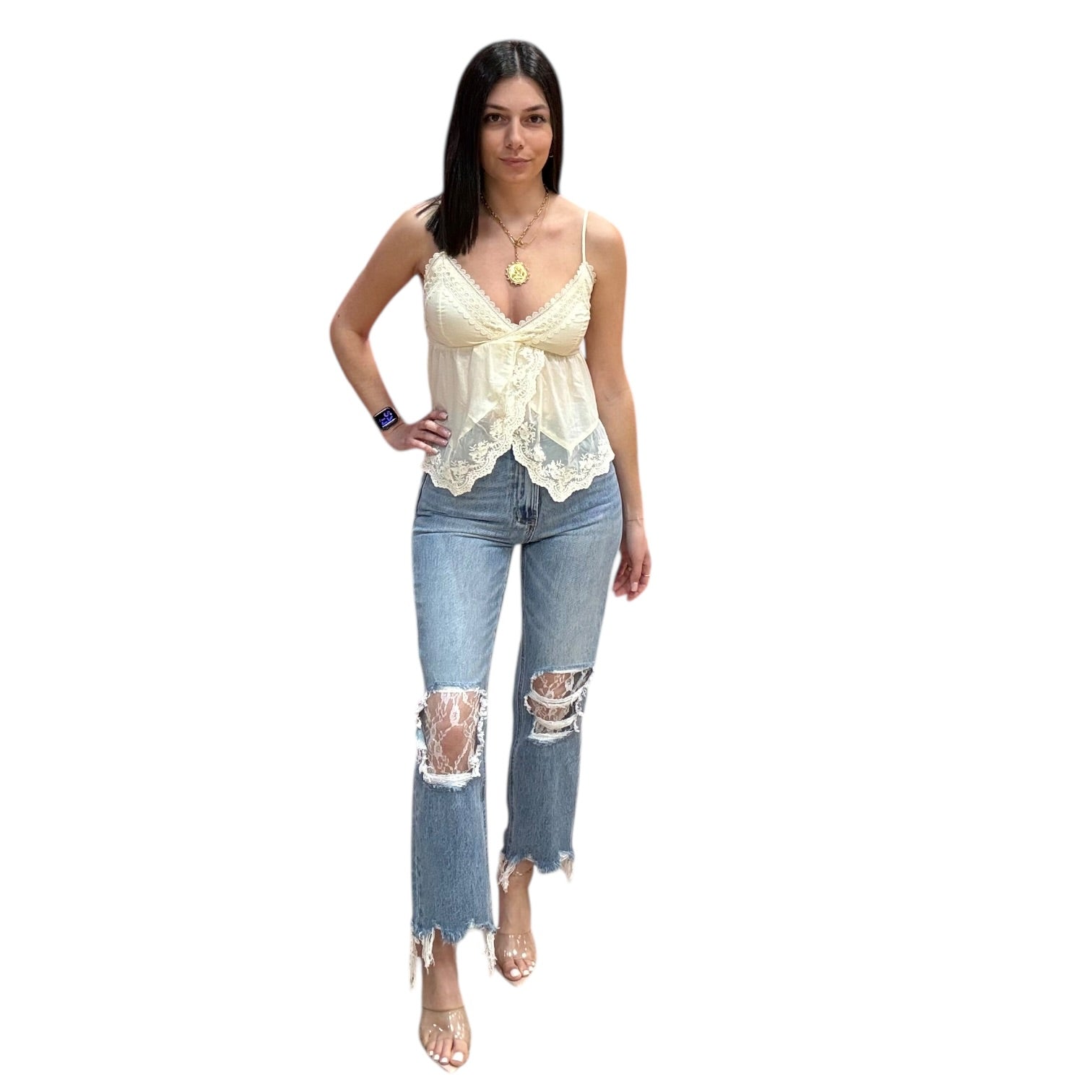 Woman wearing a cream lace top and ripped blue jeans on a white background
