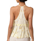 Woman wearing a light yellow floral top with a white background