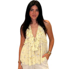 Woman wearing a light yellow floral sleeveless top on a white background