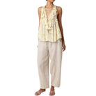 Woman wearing a yellow floral top and beige pants on a white background