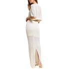 Woman wearing a white knit outfit with a high slit on a white background