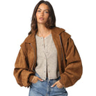 Woman wearing a brown jacket over a beige cardigan on a white background