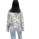 Person wearing a camo patterned jacket and jeans on a white background