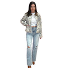 Woman wearing a patterned jacket and ripped jeans on a white background